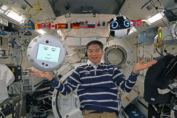 Dos robots flotando en el interior de la Estación Espacial Internacional, representando cooperación internacional e innovación tecnológica.