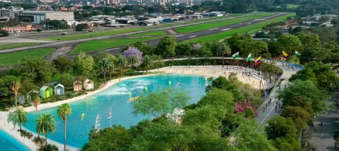 Vista aérea del Gran Parque Medellín con pista de BMX, playa artificial y complejo acuático, destacando deportes en vivo.